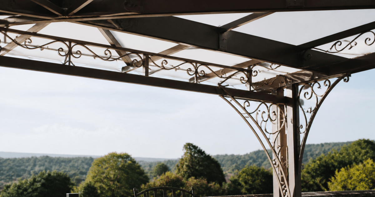Structure metallique ornementale surplombant terrasse avec poutres entrecroisees