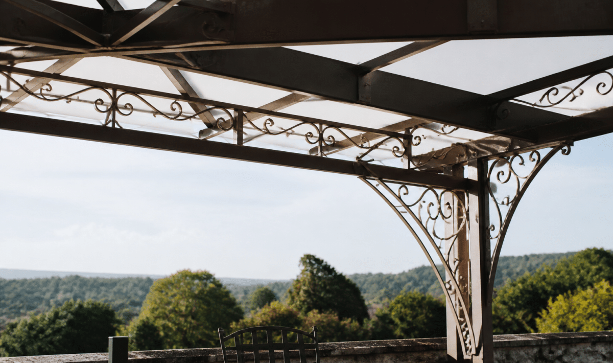Structure metallique ornementale surplombant terrasse avec poutres entrecroisees