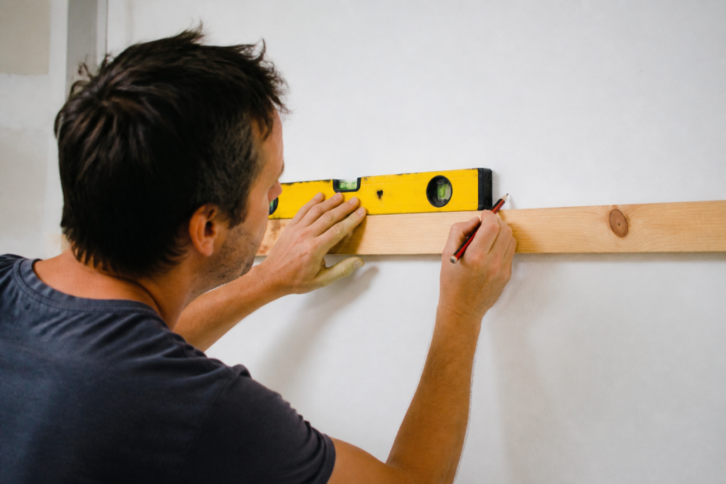 Tracage tasseaux bois crayon niveau mur blanc