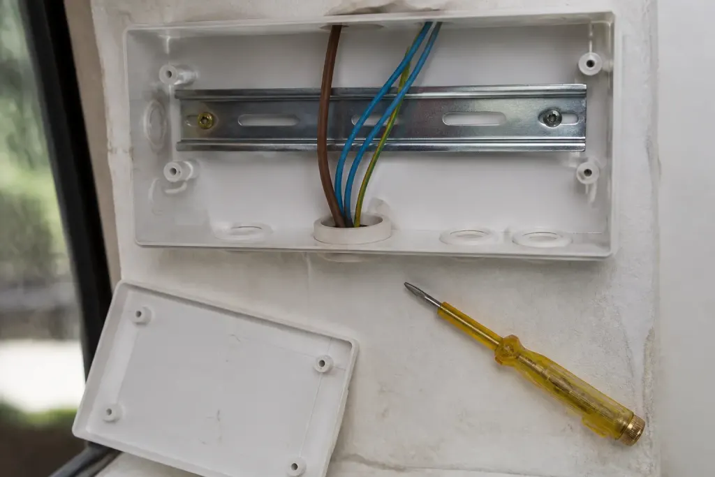 Coffret ouvert, rail DIN et testeur de tension jaune