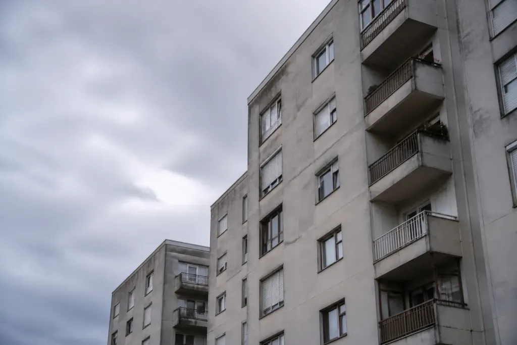 Grands immeubles gris et balcons sous ciel nuageux